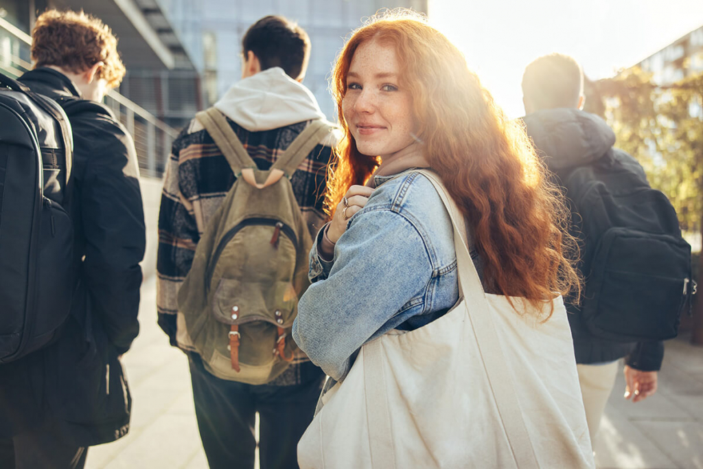 Young red haired college student walking on campus